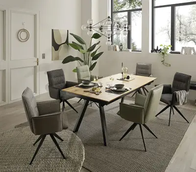 Modernes Esszimmer mit rechteckigem Massivholztisch, sechs bequemen Polsterstühlen in verschiedenen Grautönen und dekorativen Akzenten in hellem, freundlichem Raum.